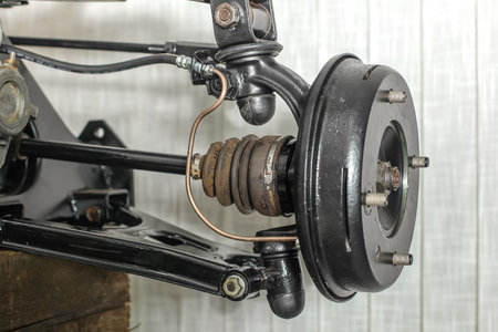 Front suspension members of an older car with new brake drum exposed with spindle, ball joints and steering rack visible.の写真素材
