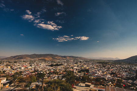 Panorama of Oaxaca, Mexico, on a sunny day with blue sky, looking from Benito Juarez statue above the city. Some white clouds are seen in the centre of the frame.の写真素材