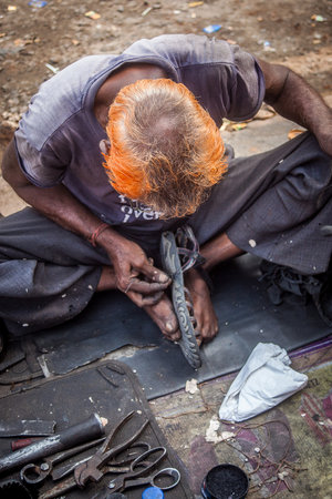 A man is fixing shoes on the street in Jaipur, India. Focus on his orange hair.の写真素材