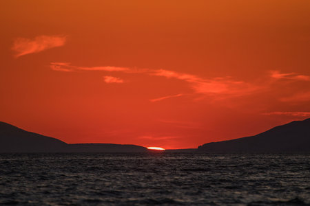 Evening view of croatian coast close to Karlobag with sunset around island of Pag and Rab. Sun just about to set behind two hills into the sea.の写真素材