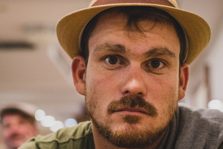 Profile portrait of a young handsome caucasian man with a slight beard and a light brown thatched hat. Soul-less expression on his faceの写真素材