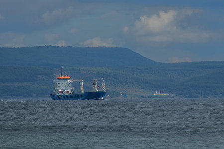 A big cargo ship or carrier traveling through the Dardanele strait in Turkey on a cloudy day.の写真素材