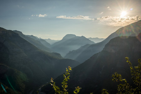 Panorama of epic view of the north albanian mountains, famous curves and hairpin turns of SH20 road above the Cem river gorge at sunrise. Sun is just rising behind the mountains.の写真素材