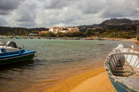 A view towards Cala Volpe, beutiful sandy beach with boats on the shore. Houses in the background.の写真素材