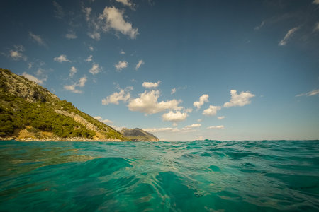 Beautiful sea water close to Cala Gonone on Sardinia. View from water towards the beach with hills rising from the beach.の写真素材