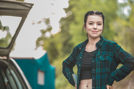 Sexy black haired girl with septum piercing and hipster shirt looking at a camera, smiling and exposing her belly. Concept of free spirit camping of hipstersの写真素材
