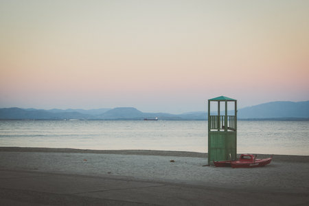 A lifeguard stand with a red rescue boat standing on a beach in a cold weather or environment. Off season for lifeguards on the beach.の素材 [FY310212316636]