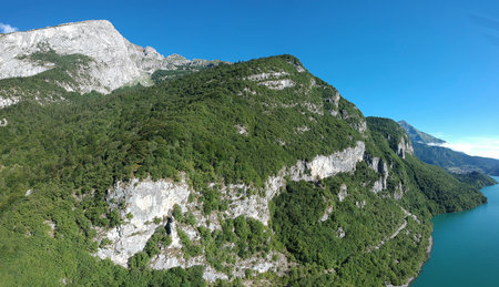 Dolomite mountains on the south part of Molveno lake, a beautiful lake in italy. Visible stone mountains and trees on a sunny morning.の写真素材