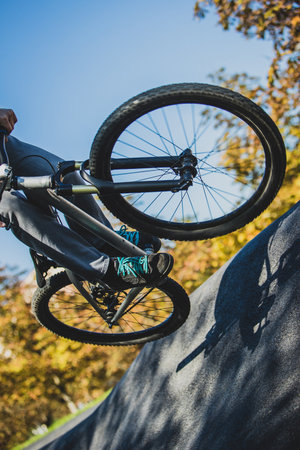 An unknown man jumping with his mountain bicycle on a n asphalt berm in a pumptrack park.の写真素材