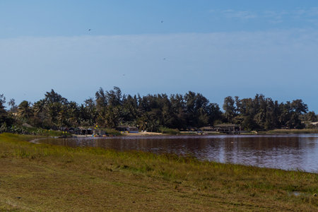 View of Lac Rose or Lake Retba in Senegal. Pink lake showing natural beauty and rich color on a sunny day. View of lake coastline and artisanal shops and bars in the background.の写真素材