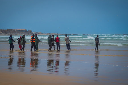 DAKAR, SENEGAL, FEBRUARY 18 2017:  A row of local fishermen pulling the rope with fishing net out of the water on the picturesque beach of Yoff in Senegal, Africa.のeditorial素材