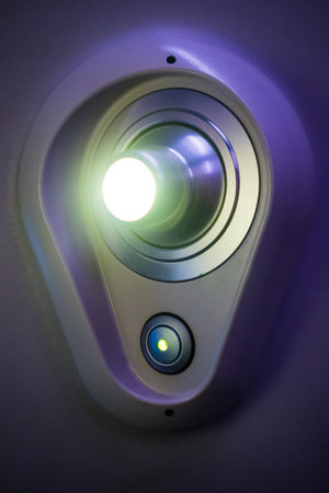 Reading lamp in a first class airline seat. Courtesy light in a plastic holder turned on with a...