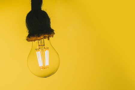 Close up view of a transparend LED light bulb resembling an old tungsten lamp on a yellow background...