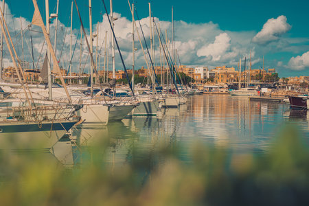 Beautiful view of marina in Valletta in Malta on a sunny day. Some greenery in the foreground and fluffy clouds on the sky.の写真素材