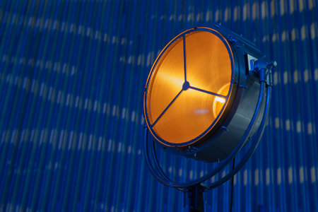 Bright industrial vintage stage lamp or reflector, with tungsten lamp in yellow color and blue background at an event.の写真素材