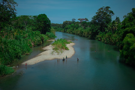 A group of locals is taking a bath in a river nearby. Typical leisure activity in a river in Costa Rica.の写真素材