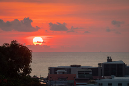 Early morning sunrise in Limon, Costarica, view from the hill above the city, church and palm trees in the background with visible carribean sea.の写真素材