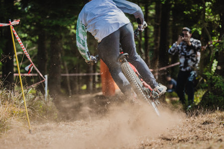 Rear view of a mountain biker racing downhill, debris and dirt flying from rear wheel. Man shredding on mountainbike, back view.の写真素材