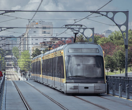 Tram of porto is moving over the famous metal bridge over douro river, with cityscape of porto in the background. Cloudy dayの写真素材