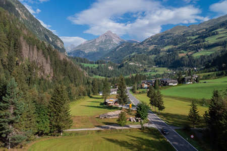 Valley of heiligenblut, looking towards the Grossglockner mountain on a sunny summer day. Green meadows and typical houses around the roadの写真素材