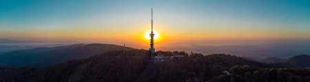 Early morning sunrise panorama of Sljeme above Zagreb with visible antenna tower, big massive hill and layers of fog below in valley. Epic panorama above zagrebの写真素材
