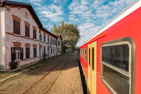 Picturesque train station of Podgorje on Istrian train line. Magnificent stone building viewed from a red passenger trainの写真素材