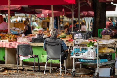 Man selling products in Market of Pula, Croatia on a sunny day. Typical market stalls with part which is selling fresh fruit and vegetablesの写真素材