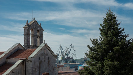 Beautiful church in Pula, croatia with visible background of cranes as part of the ship building yardの写真素材
