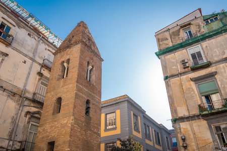 Belltower of pietrasanta complex is rising on the edge of a building in the narrow streets of Napoli old town. Small old brick belltower in the cityの写真素材