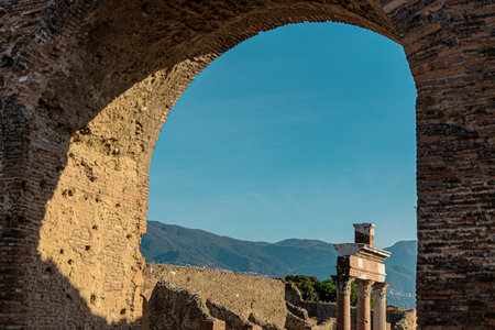 Pillars and arches in Pompei archeological site, with visible blue skies and afternoon sun, casting nice shadows.の写真素材