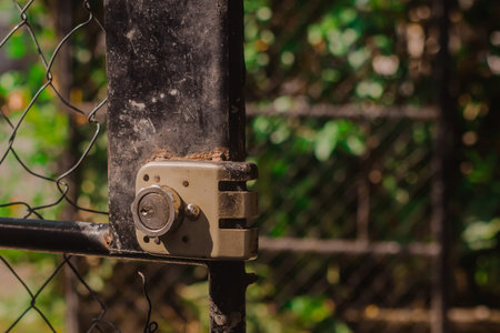 Old metal lock with cylinder in a door frame with fence. Typical entrance of an old garden or...