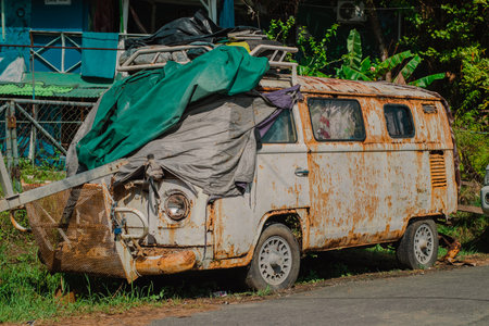 Broken and decaying van or bus from the seventies is rotting on green grass. Waste of a good old timer car.の写真素材
