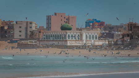 Mosque on the beach at Yoff Dakar, Senegal, standing next to crowded beach with seagulls. Typical african scene at the beach.の写真素材