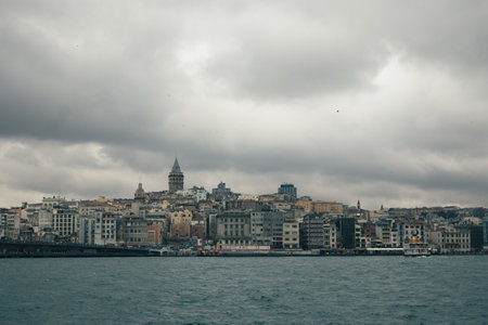 dark and cold panorama of istanbul city looking towards galata tower over the murky waters.の写真素材