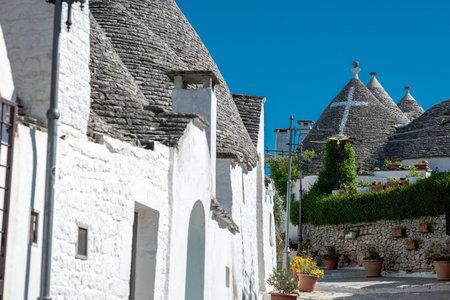 Beautiful stone of Trulli houses with white walls, narrow streets, decorated with flowers, palm trees and other decorations. Spring day, warm with sun and blue skies Selling souvenirsの写真素材