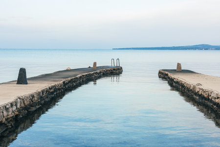 Two piers on left and right at a bay in Privlaka, Croatia. Early morning feeling in autumn, with calm seas and nobody around. Visible stairs into the water.の写真素材