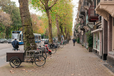 One of many streets in Amsterdam, with wite pavement, parked bicycles and tram rolling through the streets.の写真素材