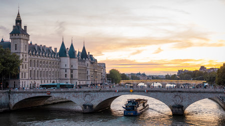 Lovely evening scene at the bridges over seine river in paris, with sun setting down in the distance. People and transport in direction of notre dame.の写真素材