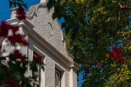 Beautiful colonial facade in white color on Dorp street, famous alley in Stellenbosch on a sunny summer day. Visible greenery and foliage with blue skiesの写真素材