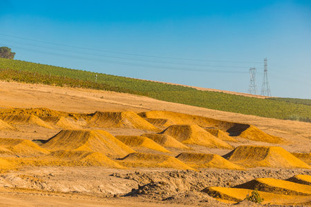 Freshly built jumps and berms in a dirt park in south africa. View of orange soil in shape of jumps and tables, green vineyard in the backgroundの写真素材
