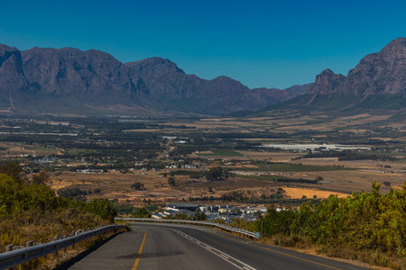 View down from paarl mountain toward eastern part of paarl city with industrial zone close by and Franschoek in the background, road in the foregroundの写真素材