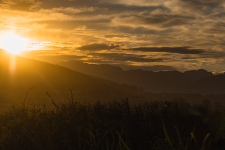 Early morning in the plains of south africa close to Paarl and Stellenbosch. Visible sun rising above the mountainの写真素材