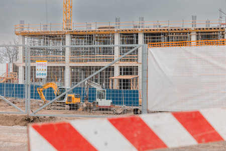 A construction site with a multi-story building under construction, featuring scaffolding and a...