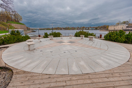 circular stone plaza with benches along the Narva River promenade in Narva, Estonia. Surrounded by...