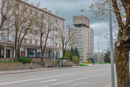 Narva street scene features a wide road, a bus stop with a person waiting, and a scooter nearby....