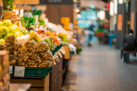 A vibrant market stall in Tallinn overflows with fresh produce, including potatoes, cabbages, and peppers. The bustling indoor scene, with blurred shoppers in the background, highlights the lively atmosphere and local flavors.の写真素材