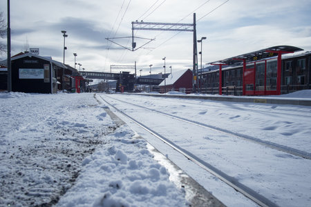 Snow-covered re railway station in Sweden during winter. Train tracks and red shelters stand out against the white snow and overcast sky, capturing the calm beauty of a Scandinavian winter scene.の写真素材