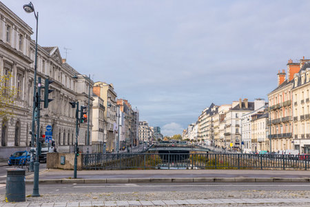 A calm canal runs through the center of Rennes, lined with elegant historic and modern buildings. Trees with autumn foliage reflect in the still water, creating a peaceful urban scene.の写真素材