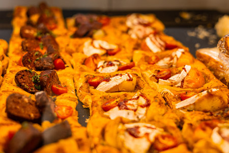 Close-up of assorted mini pizzas on a tray. Toppings include meatballs with herbs, cherry tomatoes,...