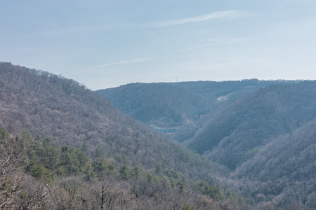 A broad, hazy view of a steep, wooded valley in the Karst region, with a massive concrete bridge viaduct visible in the distant center.の写真素材